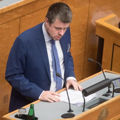 Urmas Reinsalu vid ett talarpodium. 
