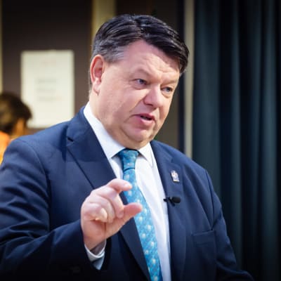Petteri Taalas i kostym gestikulerar med en hand.
