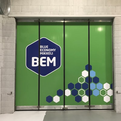 Vihreä taiteovi, jossa on BEM-osaamiskeskuksen logo.