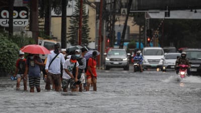 Människor i vattenmassor i samband med översvämning i Makati, Filippinerna