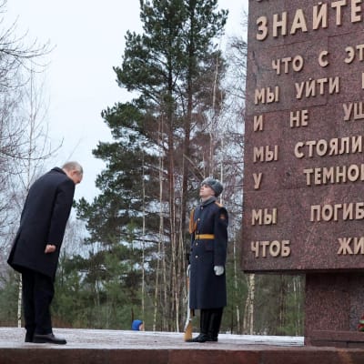 Vladimir Putin kumartaa muistomerkin edessä.