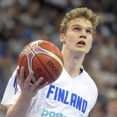 Basketspelaren Lauri Markkanen i farten med bollen i högsta hugg.