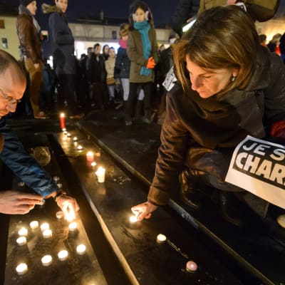 Personer tänder ljus till minnet av offren i Charlie Hebdo-massakern