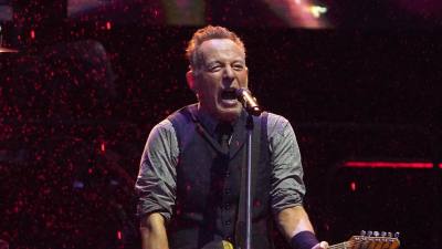 Bruce Springsteen laulaa kitaran kanssa lavalla kaatosateessa.