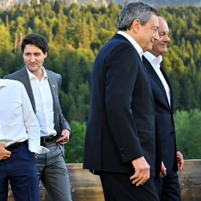 Viisi maailman johtajamiestä naureskelee ruskaisessa, aurinkoisissa alppimaisemassa. Yhdysvaltojen presidentti Joe Biden pitää kättä Ranskan-kollegansa Emmanuel Macronin olkapäällä.