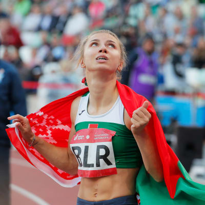 Kristina Timanovskaja tittar uppåt med den belarusiska flaggan.