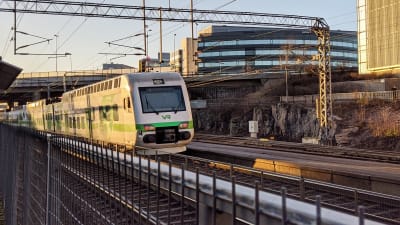 Ett lokaltåg kör i soluppgången förbi Kottby station i Helsingfors.