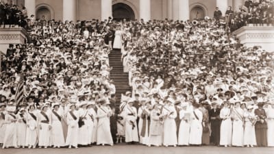 Svartvitt foto på hundratals vitklädda, kvinnliga suffragetter på trappan till Capitolium.