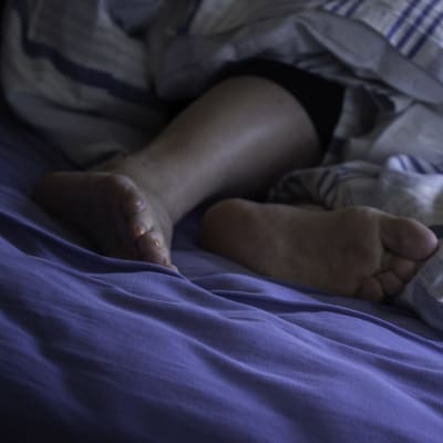 Fötter på en sovande person i en säng.