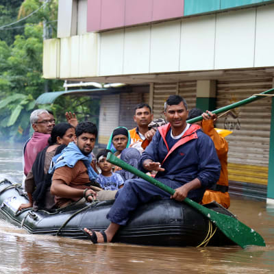 Människor tar sig fram i en gummibåt i Kerala i augusti 2018.