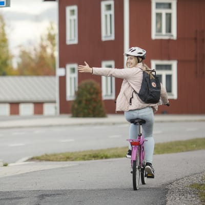 En cyklist indikerar att hon ska vända till vänster i en korsning.