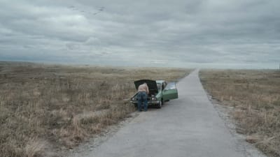 En man och en bil mitt i ett öde landskap.