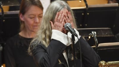 Patti Smith med händerna över sitt eget ansikte under Nobelfesten i Stockholm.