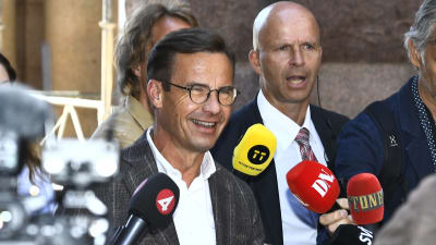 En solbränd och glad Ulf Kristersson möter pressen utanför Sveriges riksdag.