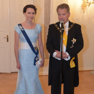 Presidenten och hans maka står festklädda vid en mikrofon