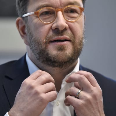 Minister Harakka förklarar, med händerna uppe.