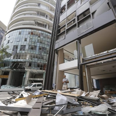 Personer står nära en skadad byggnad efter explosionen i Beirut. 