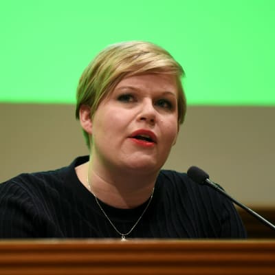 Annika Saarikko framför en liten mikrofon.