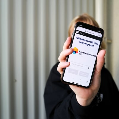 Någon visar valkompassen på mobilen.