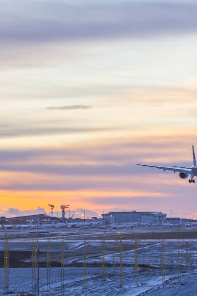 Ett Finnairflyg är på väg att landa vid Helsingfors-Vanda flygplats i solnedgången.