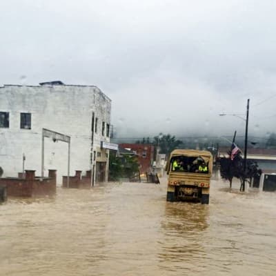 Arme'bil kör längs översvämmad gata.
