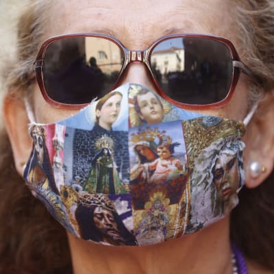 Kvinna i solglasögon bär munskydd med tryck av religiösa motiv. 