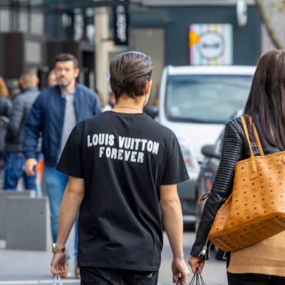 Louis Vuitton -teksti miehen t-paidassa ja naisella Vuittonin laukku.