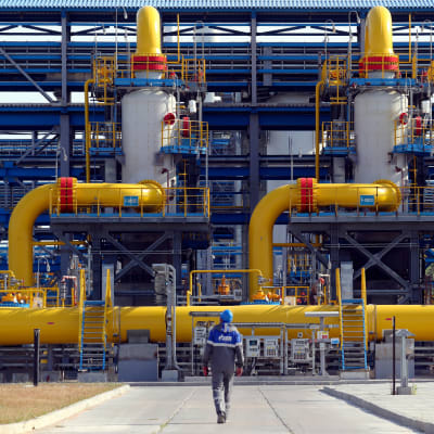 En arbetare går framför det ryska energibolaget Gazproms enhet nära Sankt Petersburg i juli 2021.