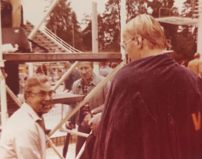 Vasemmalla uimavaömentaja joka katsoo hymyillen Otso Kauttoa, joka on selin kameraan kuvan oikeassa reunassa kylpytakki olkapäille heitettynä.