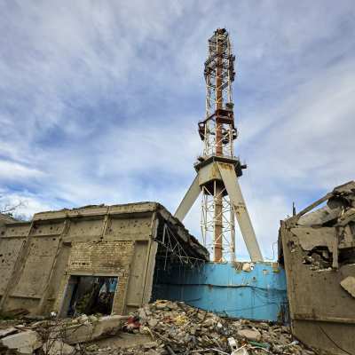 Nedre halvan av tv-tornet i Charkiv står kvar. Kring tornets fot står trasiga byggnader i betong.