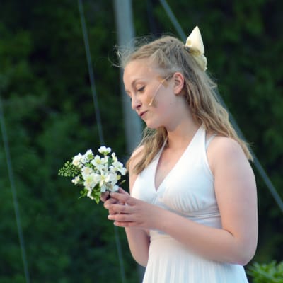 Emilia Ekström står med en bukett plastblommor i handen.