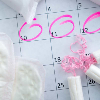 Tamponger, bindor och en kalender markerad med rosa ringar runt det som ska föreställa dagar man har mens. 