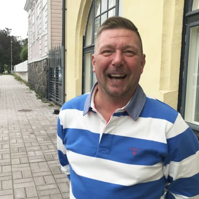 man i blåvitrandig skjorta skrattar