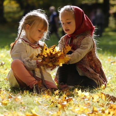Flickor leker med höstlöv.