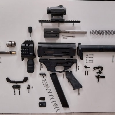 3D-tulostettu ampuma-ase on purettuna osiin valkoiselle alustalle.