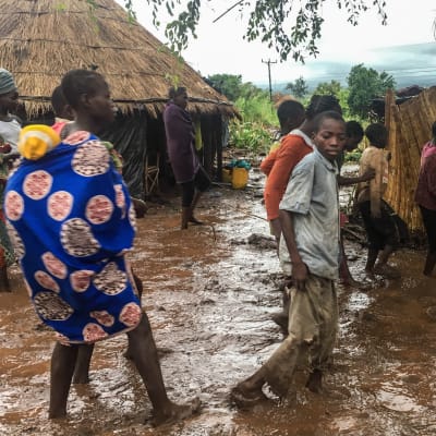Invånare i en by går längs en översvämmad väg i Moçambique.
