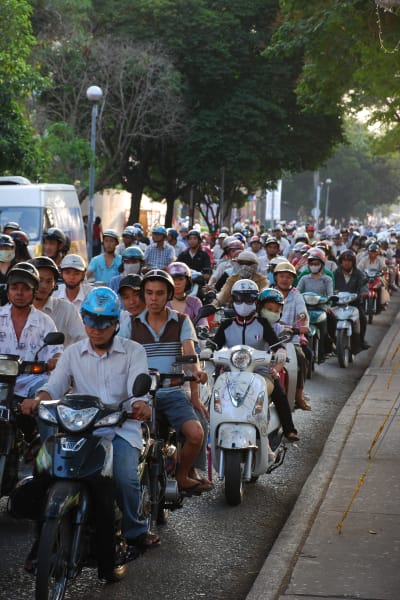 Många mopeder och motorcyklar trängs på den lilla gatan.