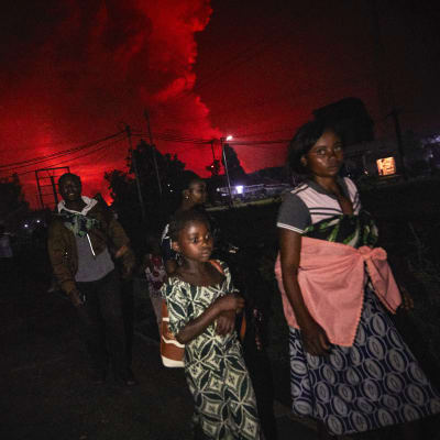 Kongoleser med packning flyr undan vulkanen Nyiragongos utbrott. Himlen bakom dem är färgad röd av utbrottet.