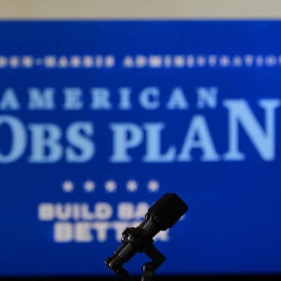 Joe Biden håller tal. I bakgrunden syns en plansch med texten "American Jobs Plan".