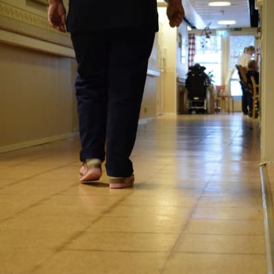 Två ben, en person som går i en korridor vid ett äldreboende.