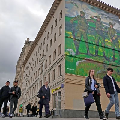 Ihmisiä kävelee kadulla Moskovassa 20. syyskuuta 2022. Takana näkyy kerrostalon seinän korkuinen muraali, johon on maalattu kolme Venäjän "erikoisoperaatioon" osallistuvaa sotilasta.