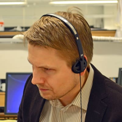 Aarne Kiviniemi kuuntelee kuulokkeilla.