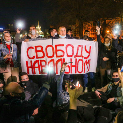 Demonstranter samlas kringen ett plaket med texten Frihet för Navalnyj på ryska.