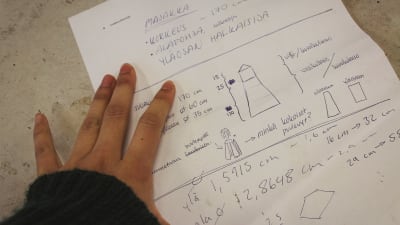 Käsi ja paperi, johon piirretty ja kirjoitettu suunnitelmia Majakka-nimisen veistoksen toteuttamiseksi.