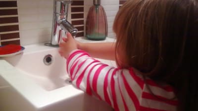 Flicka tvättar händerna.