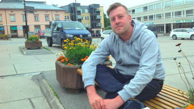 Kristian Karnell sitter på en bänk på Rådhustorget i Ekenäs.