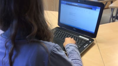 Elev skriver på dator