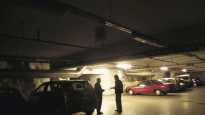 Två män byter varor i en parkeringshall