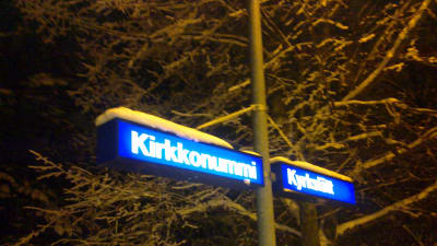 Ortnamnsskylt på Kyrkslätt station i vintertid.