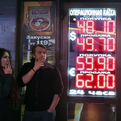 Ryssari Moskva  röker vid en informationstavla som visar valutakurserna 28.11.2014.
